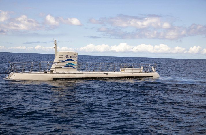 The Atlantis Submarine is seen from above the water during the day, showing its sleek design and readiness for another dive