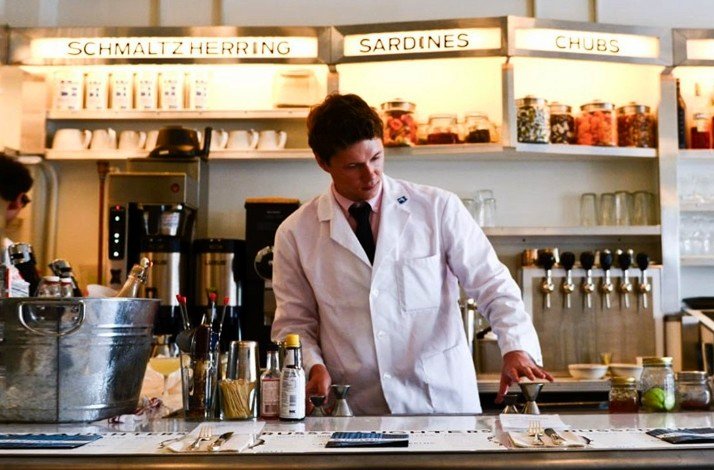 A bartender making preparations to serve decadent cocktails and passed bites in Russ & Daughters Café.