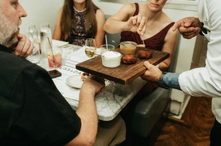 A waiter is serving ordered sets to a group of guests at Russ & Daughters Cafe