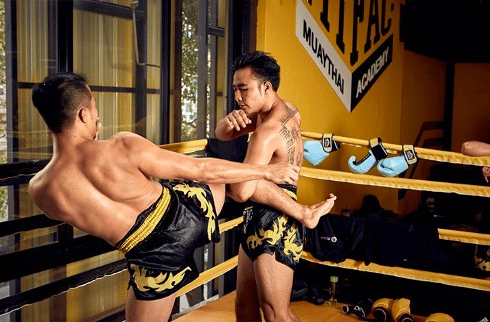 A Muay Thai fighter lands a kick to his opponent’s torso during training.