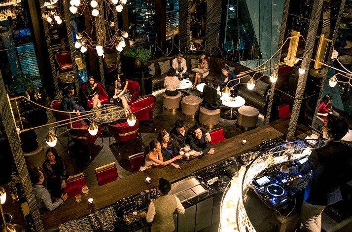 Diners enjoy drinks at Park Hyatt Bangkok's plush Penthouse Bar + Grill.