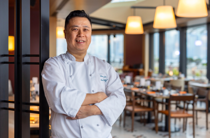 Chef in white uniform standing in a restaurant.