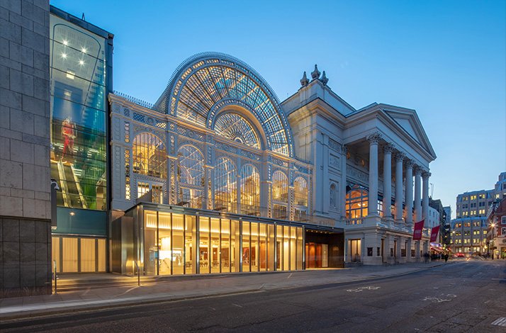 Night time view of Royal Opera House in London, showcasing its classical and modern architectural styles.
