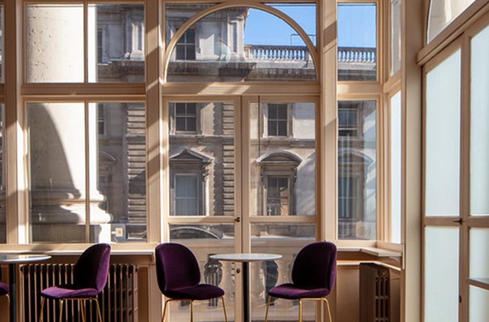 Elegant indoor seating area with purple chairs and large windows.