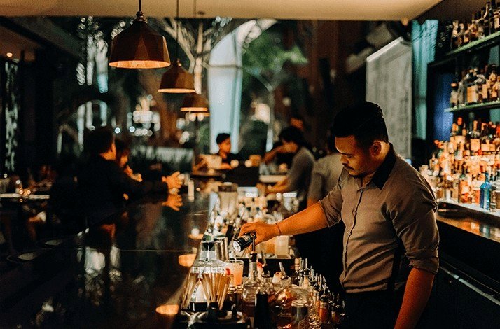A bartender pours drinks behind the counter at Merah Putih.