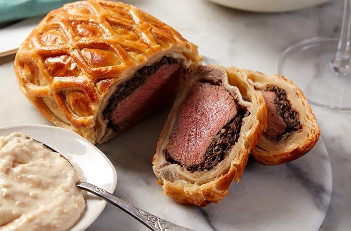 A close up of Beef Wellington paired with white sauce, served at Fortnum & Mason