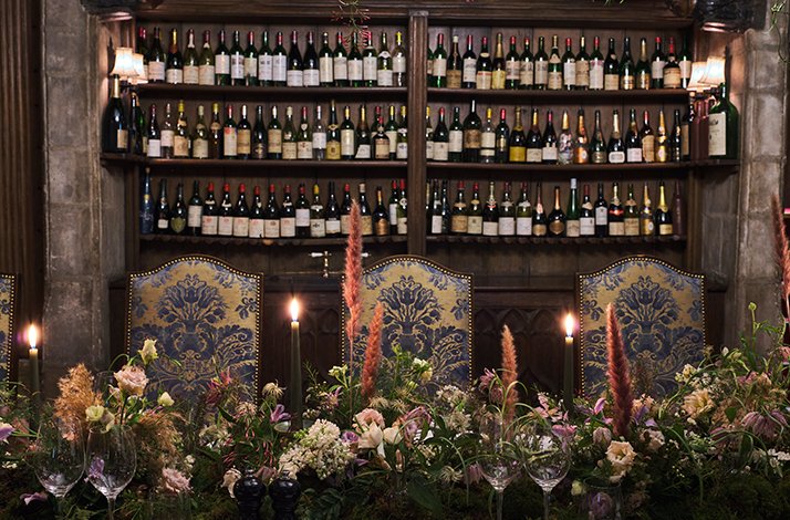 Beautifully decorated table at Fortnum & Mason with a collection of Fortnum's Favourite Wines displayed on wall shelves.