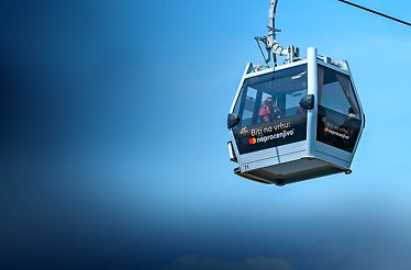 A group of passengers inside a cable car glide through the sky, showcasing the Biti na vrhu: neprocenjivo branding