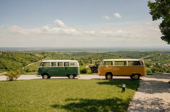 Two vintage vans are parked on a hill overlooking a green valley.