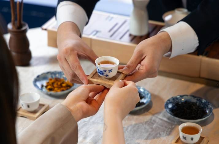 A small tea cup is handed to a guest during a tea ceremony.