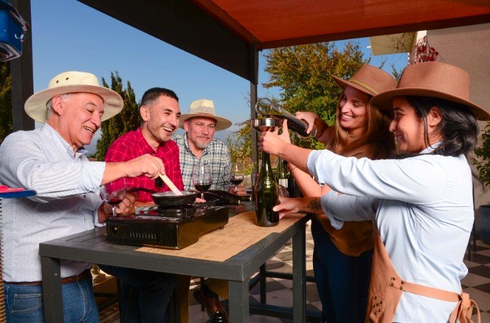 A group of people are gathered around a table outdoors, enjoying their wine tasting and having conversation at Casa Viñamar.