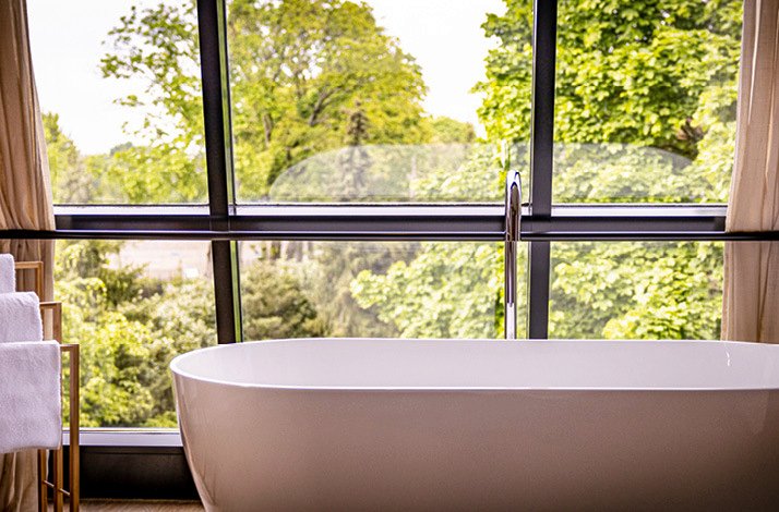 An image of a bathtub situated beside a glass window, close by is a towel rack at Hotel de Sterrenberg