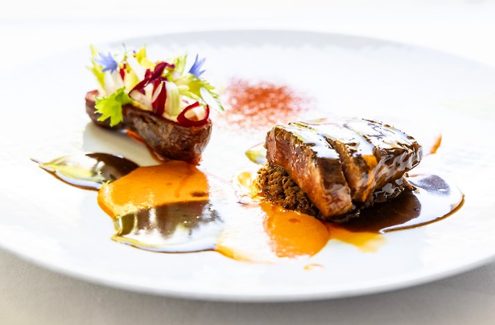 Main course featuring tender meat, colorful sauces, and edible flowers, part of the estate’s five-course gastronomic dinner.