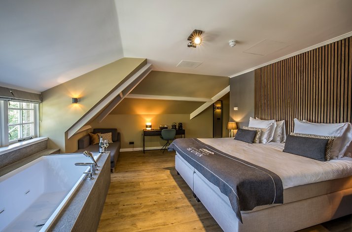 An interior photo of the Landgoed de Uitkijk  hotel room, equipped with a queen sized bed, facing a bathtub.