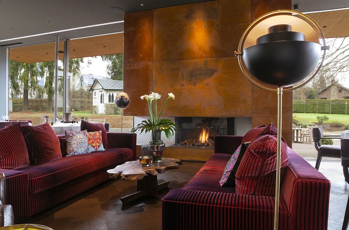 The interior of  Restaurant Le Val d'Amblève , featuring red sofas and a fireplace
