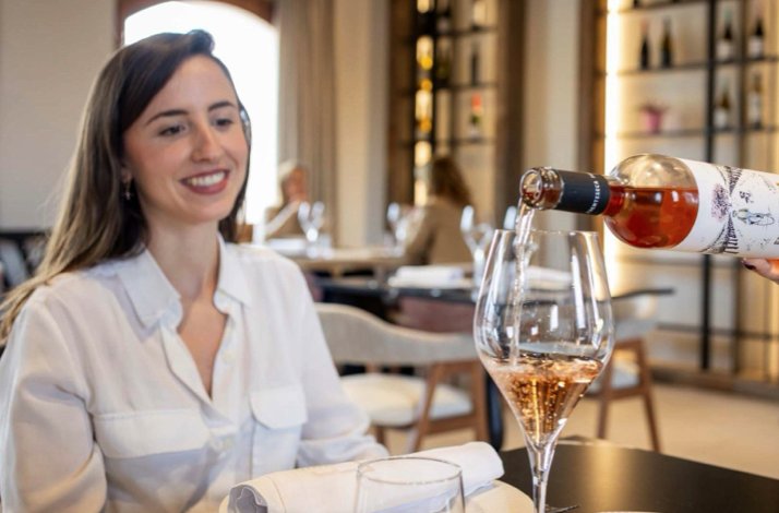 A lady watching wine poured in elegant dining space at Luxury Enoresort