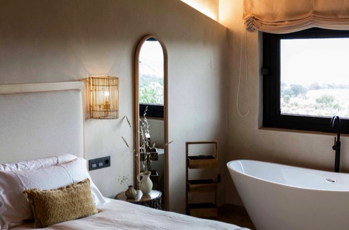 A cozy bedroom with natural decor, a standalone tub, and a window view.