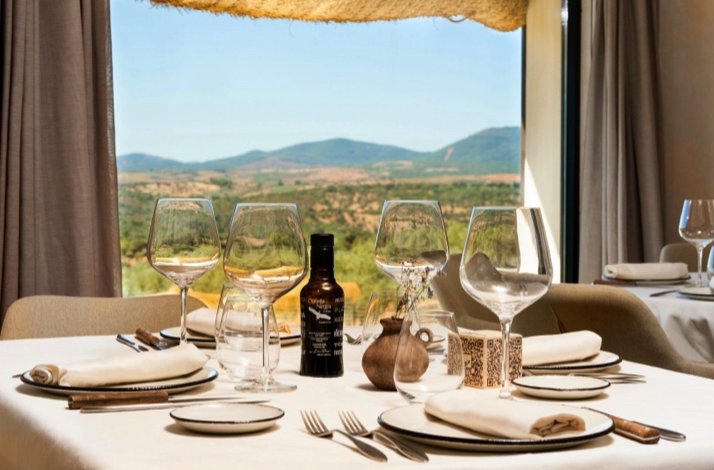 A table set for fine dining with a scenic countryside view through the window.