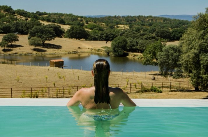 Guest relaxing in an infinity pool overlooking a lake and forested hills at Habitat Cigueña Negra.