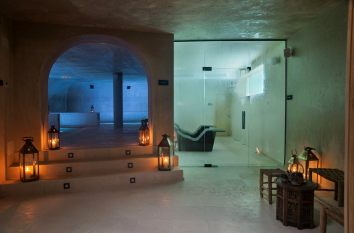 Dimly lit spa interior with arched stone walls and lanterns.