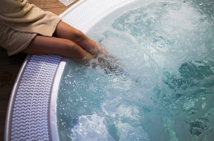 Close-up of a person dipping their legs into a whirlpool tub during a private spa session for two.