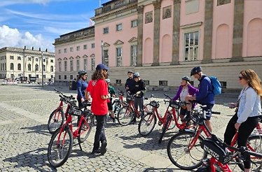 Participants of Secrets of Berlin Bike Tour listening to the guide while Uncovering Berlin's secret spots in the historical place.