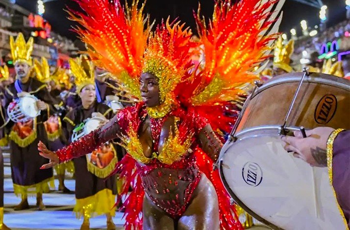 A vibrant image showcases a parade, featuring people in elaborate costumes, during a Brazilian Carnival celebration.