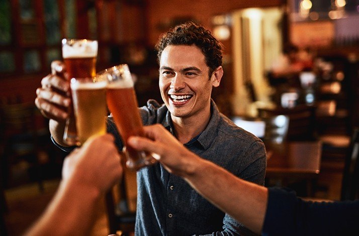 A smiling person toasting with friends on a guided tour of Rio bars.
