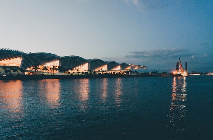 Museu do Amanhã illuminated at dusk, reflecting on the water in Rio de Janeiro.