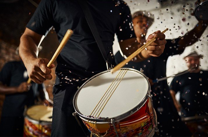 A group of people intensely playing drums, surrounded by confetti.