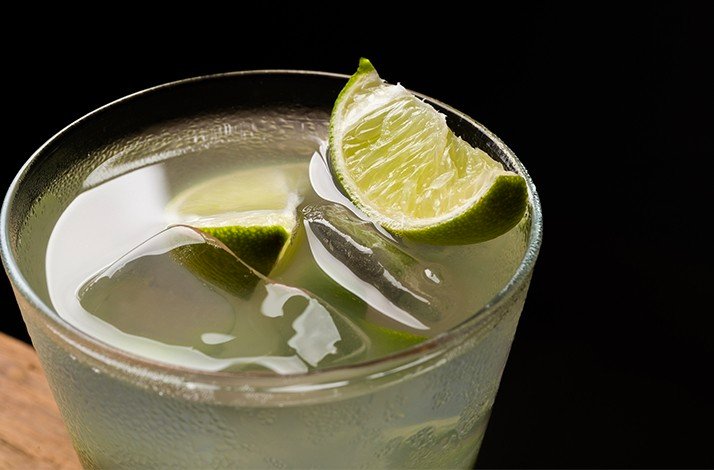 A close-up view of a glass of beverage with lime slices and ice.