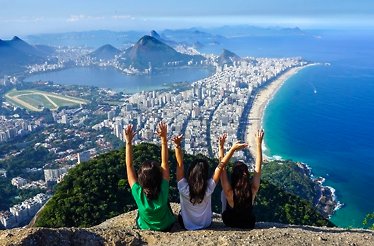 A vibrant view from Morro Dois Irmãos with three friends overlooking Rio's cityscape and beaches.