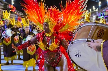 A vibrant image showcases a parade, featuring people in elaborate costumes, during a Brazilian Carnival celebration.