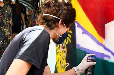 Artist carefully spray-painting a vivid mural on a wall