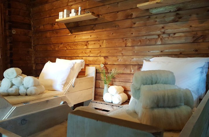 Rustic wooden spa with cozy beds and fluffy wool, perfect for relaxation.