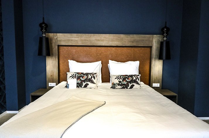 Elegant king-sized bed with plush pillows and sleek lighting in a stylish room.