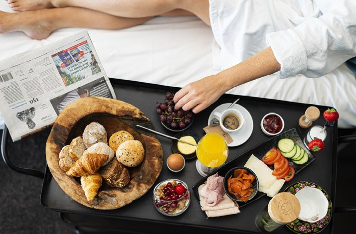 Luxurious breakfast-in-bed setup with fresh pastries, fruit, and coffee.