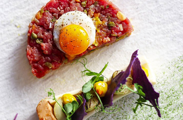 Gourmet dish featuring beef tartare, quail egg, and artistic plating