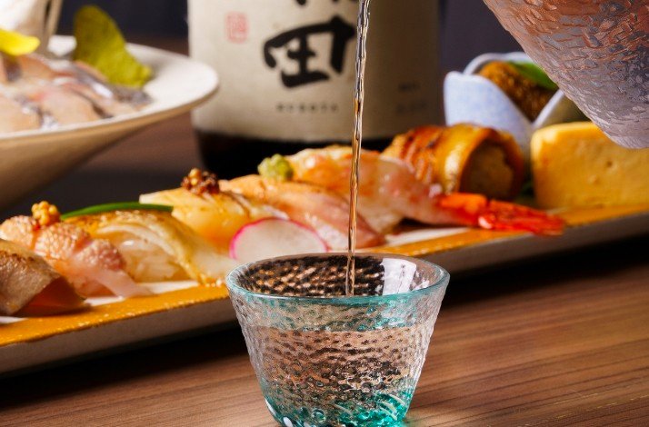 Close-up of a waiter pouring sake into a glass in ODDS & Zushi ANA