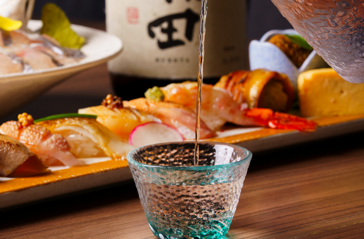 Close-up of a waiter pouring sake into a glass in ODDS & Zushi ANA