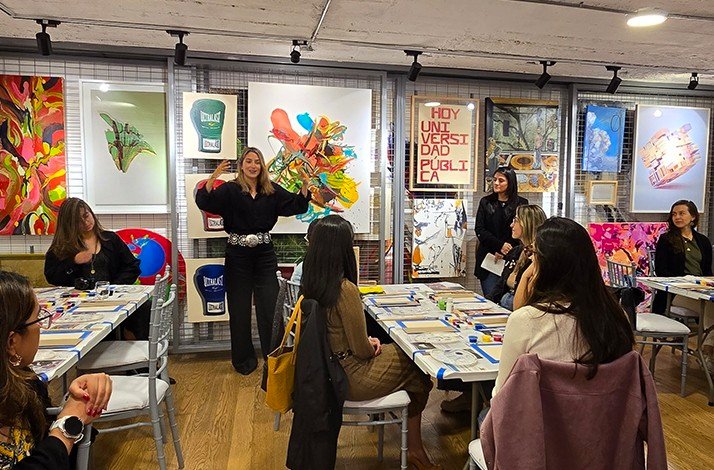 Art workshop with attendees seated, vibrant paintings, posters, and creative tools displayed around the room