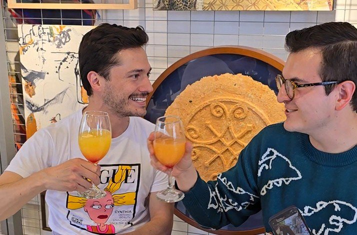 Friends sharing drinks, set against unique wall decor featuring intricate designs