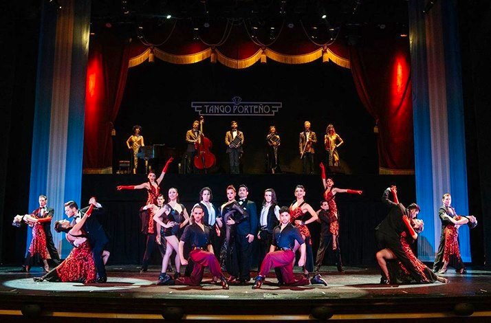 A vibrant tango performance with dancers and musicians on a grand stage