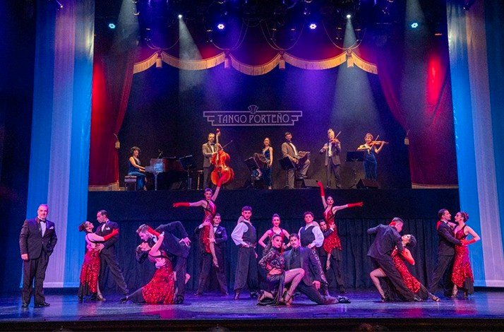 A vibrant tango performance with dancers and musicians on a grand stage