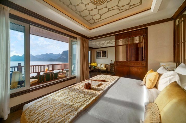 A luxurious bedroom suite at Hạ Long Bay's Heritage Line boasts a stunning view of a lake and mountains.