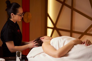 A lady is enjoying a relaxing head massage in a serene treatment room at the Shiseido Spa