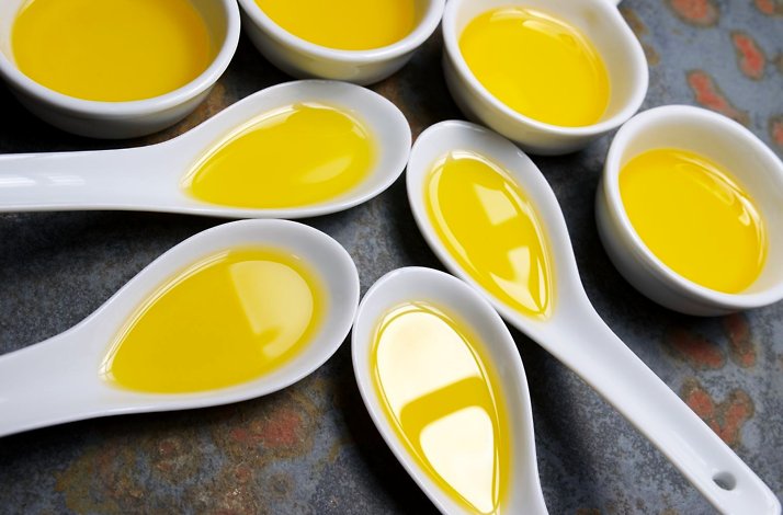 Multiple spoons filled with olive oil for tasting.