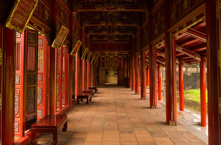 A long, red-columned hallway within the Hue Imperial City, which extends into the distance, showcasing ornate architecture.