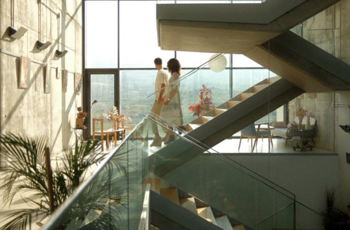 Young couple looking through floor-to-ceiling windows while making their way down the stairway at the Finca de los Arandinos hotel in Entrena, Spain.