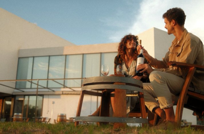Young couple sharing a bottle of wine during sunset outside Finca de los Arandinos hotel, Entrena, Spain.